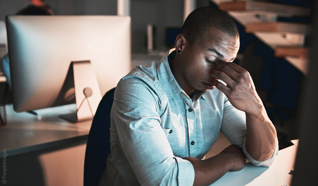 Image : un homme assis à un bureau se tient la tête