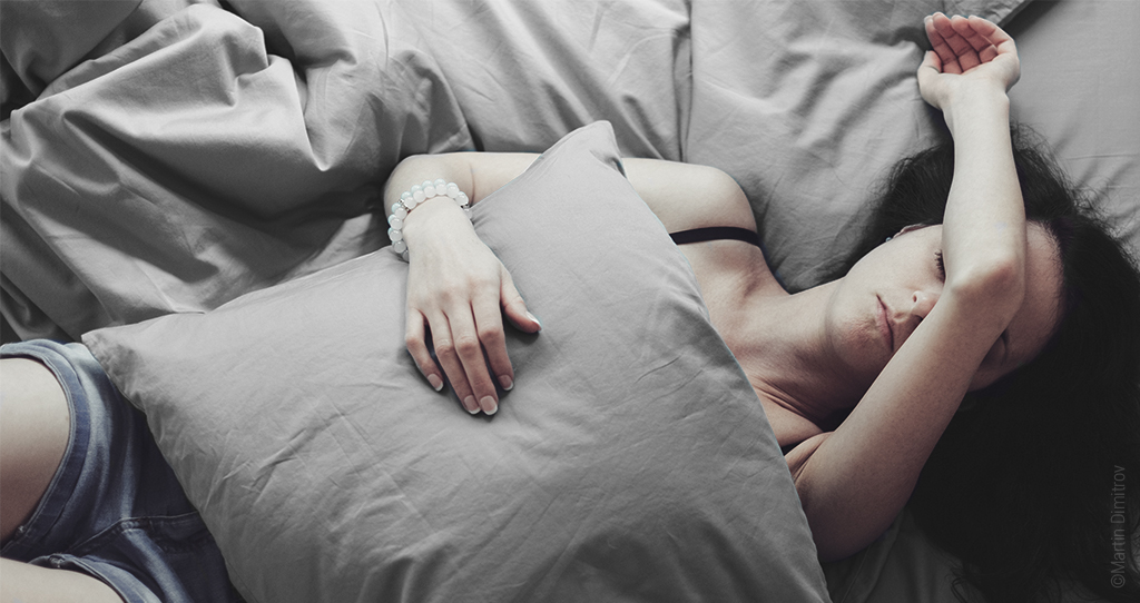 Photo d'une femme qui dort dans un lit le bras posé sur la tête