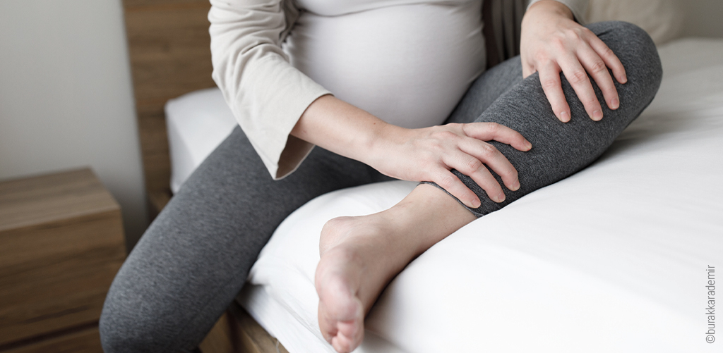 Photo d'une femme enceinte assise sur le lit, la jambre repliée