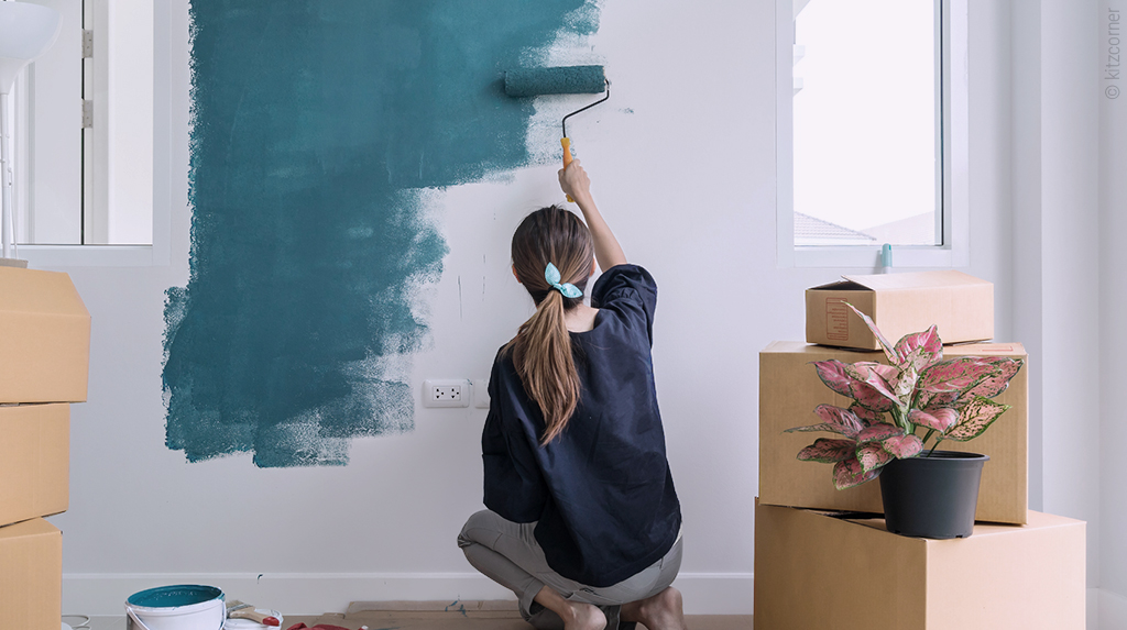 photo : une femme repeint un mur en bleu avec un rouleau