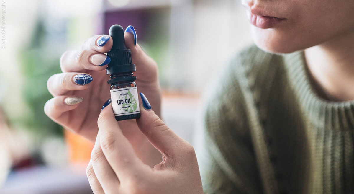 Une femme ouvre une flacons de CBD oil