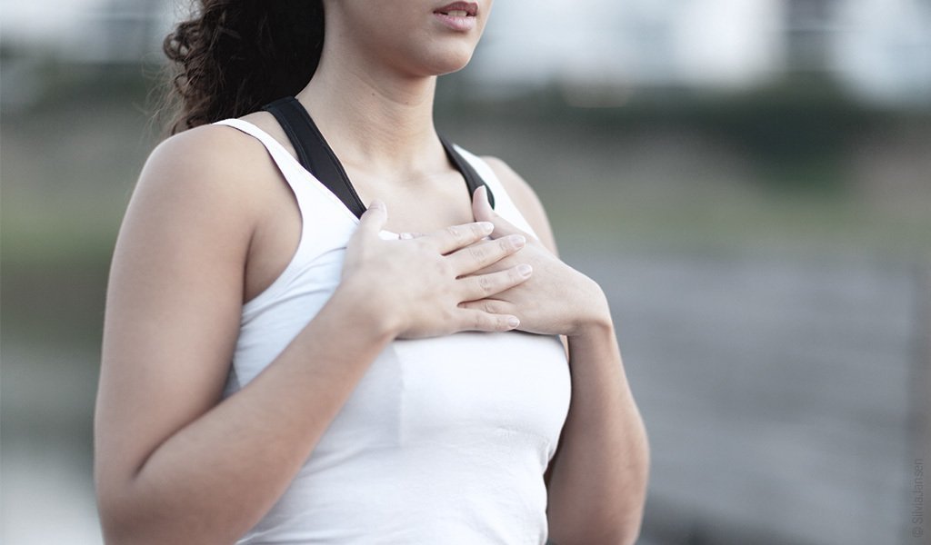 Une femme pose ses deux mains sur sont thorax