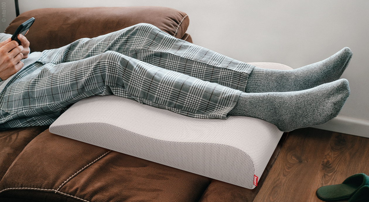 Des jambes reposent sur un coussin repose-jambes