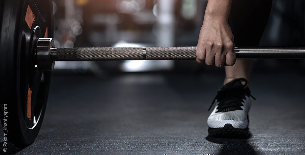 Une personne est penchée pour soulever des altères