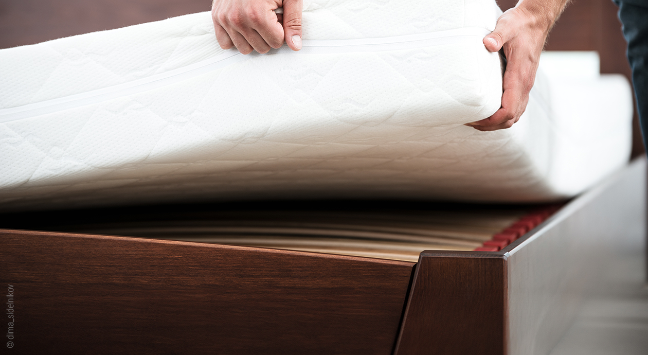 deux mains qui soulèvent le coin d'un matelas